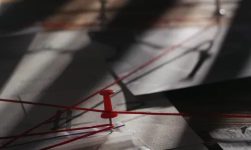 Close up of investigation board with map pinned evidences and red thread connecting clues