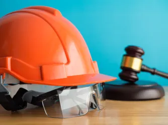 Construction helmet and worker safety glasses on table indicating legal protection