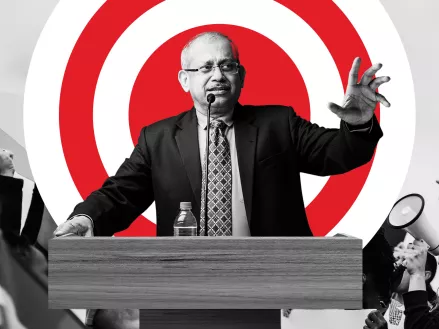 Man at a podium standing in front of a red bullseye 