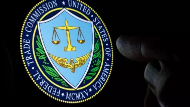 FTC Federal Trade Commission logo seen on the display in a dark room and blurred finger pointing at it