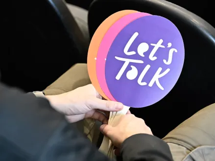 Student holding "Let's Talk" fans at an event in Utah
