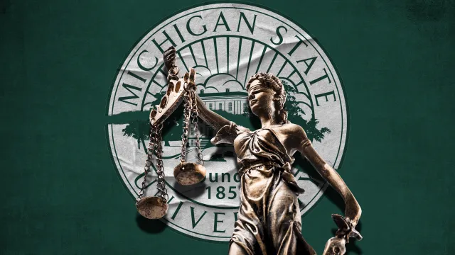 A statue of Lady Justice in front of a Michigan State University flag