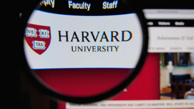 Photo of Harvard University homepage on a monitor screen through a magnifying glass 