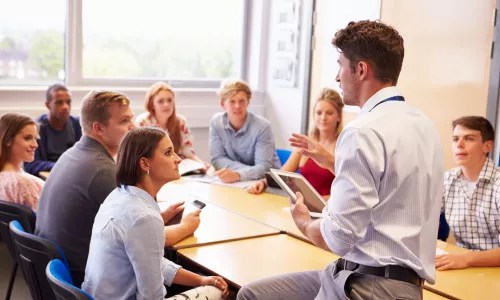 Teacher With College Students Giving Lesson In Classroom