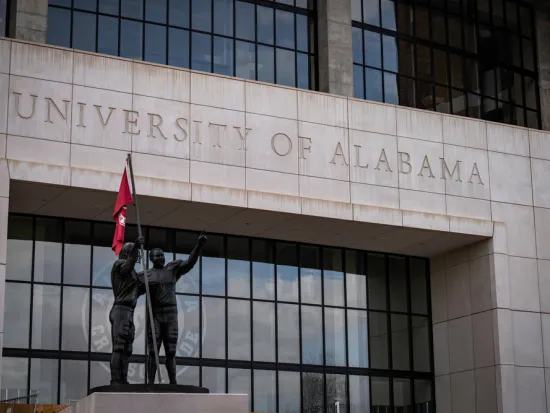 Bryant-Denny NCAA Football Stadium with statues and flag at the University of Alabama
