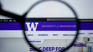 University of Washington website homepage visible on display screen under a magnifying glass