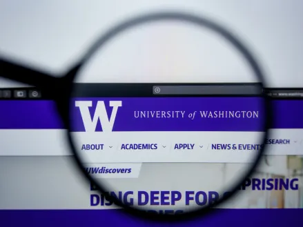 University of Washington website homepage visible on display screen under a magnifying glass